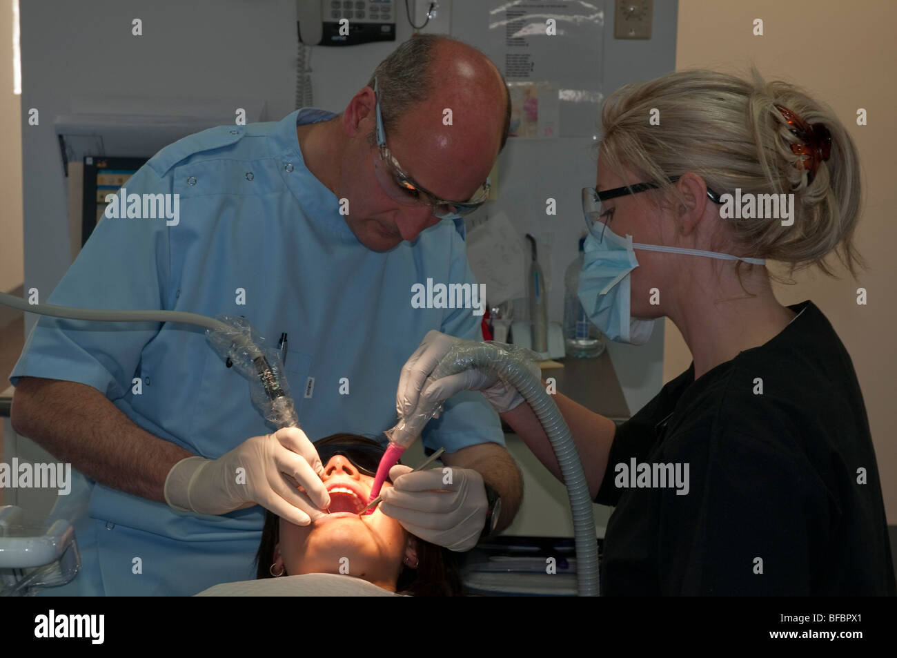 Dentista e assistente dare ad un paziente in una moderna chirurgia dentale di un regolare checkup Foto Stock