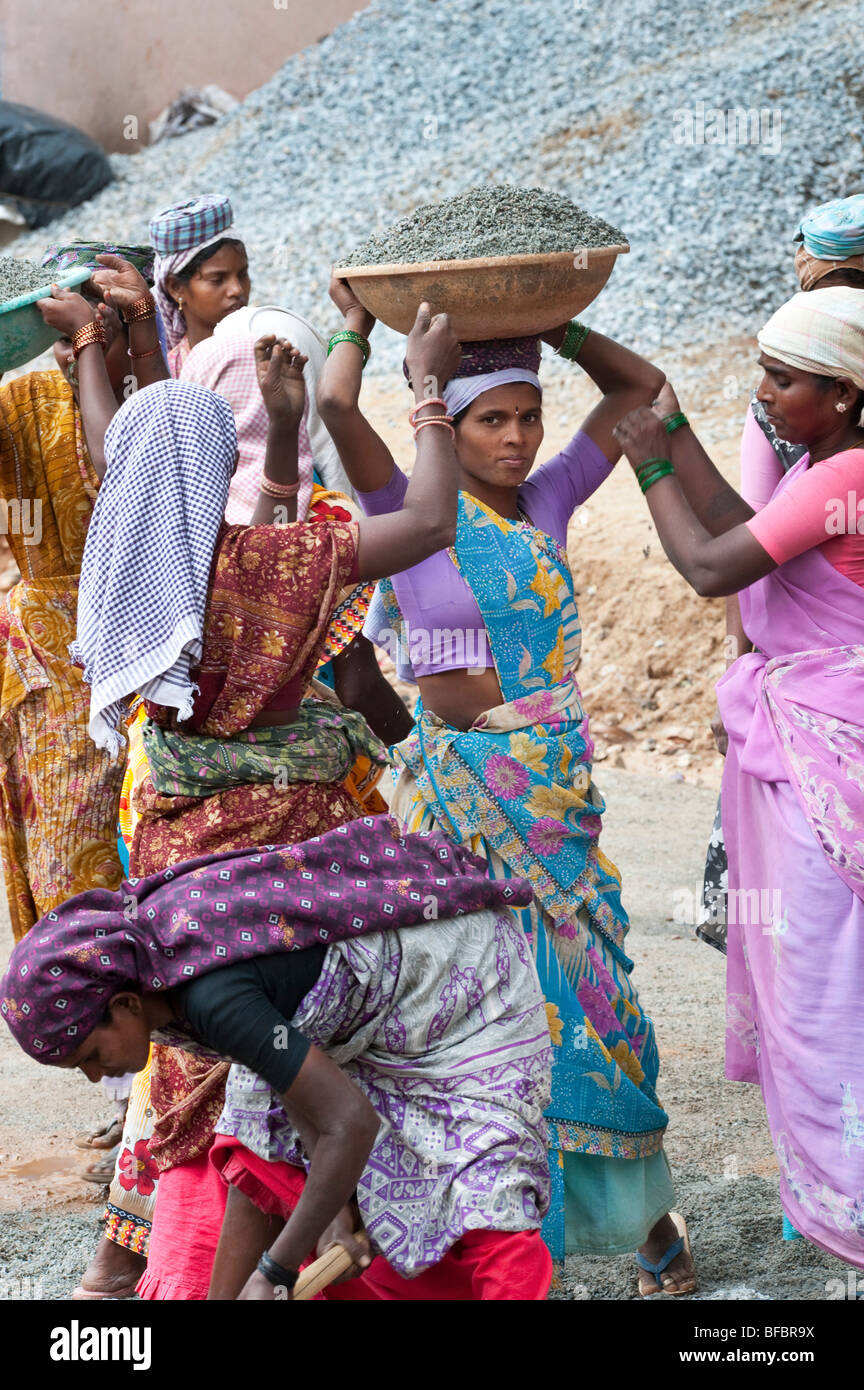 Donna indiana che trasportano pietre in una ciotola sul suo capo per rendere concreta mentre lavorano sulle strade in Puttaparthi, Andhra Pradesh, India Foto Stock