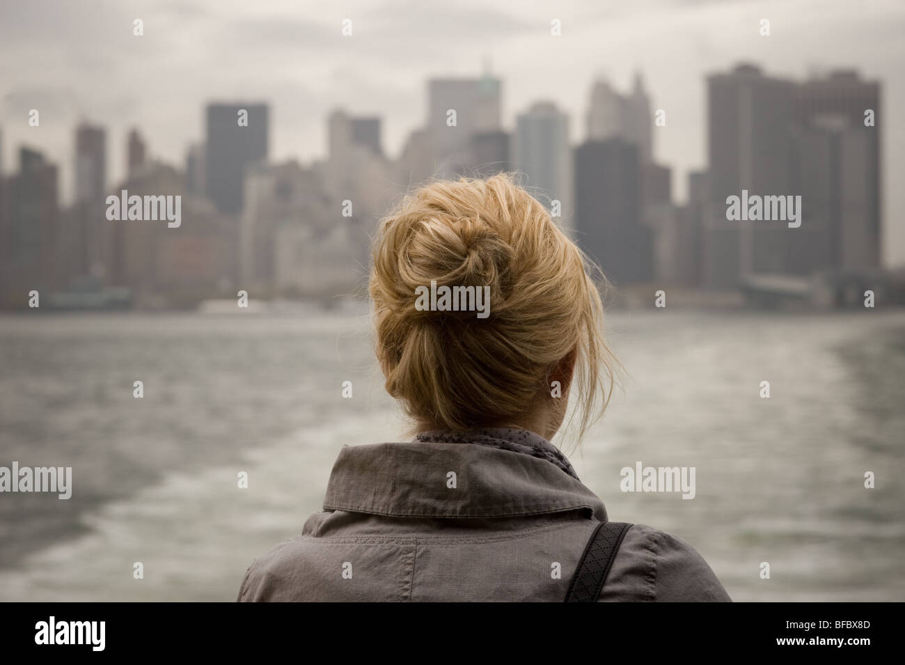 Donna bionda su Staten Island Ferry, New York City in background Foto Stock