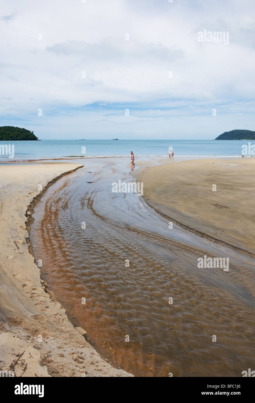 I turisti a piedi attraverso un ruscello su Pantai Tengah spiaggia di Langkawi in Malesia Foto Stock