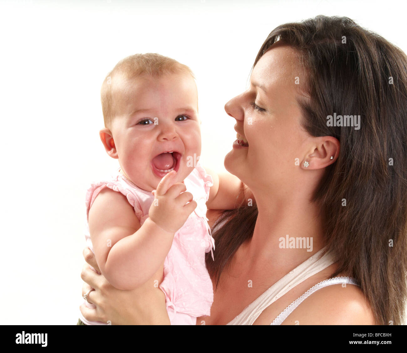 Brunette mamma gioca con la bionda bimba su sfondo bianco. venti qualcosa di mamma e un anno di età bambina Foto Stock