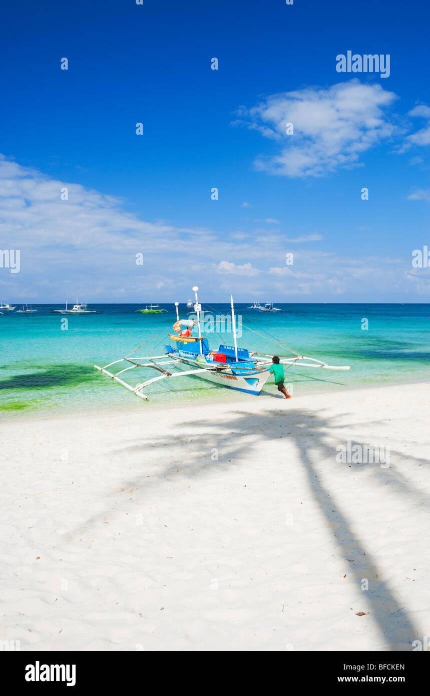 L'uomo spingendo barca in mare e l'ombra del palm tree Boracay; Il Visayas; Filippine. Foto Stock