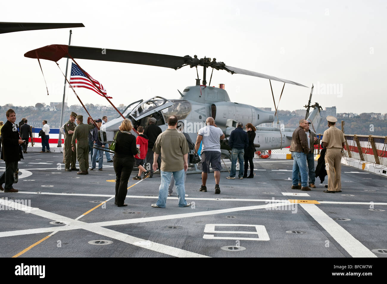 I visitatori si radunano intorno Marine elicottero Cobra & i suoi piloti sul ponte di volo della USS New York ormeggiata presso il Molo 88 in New York Foto Stock