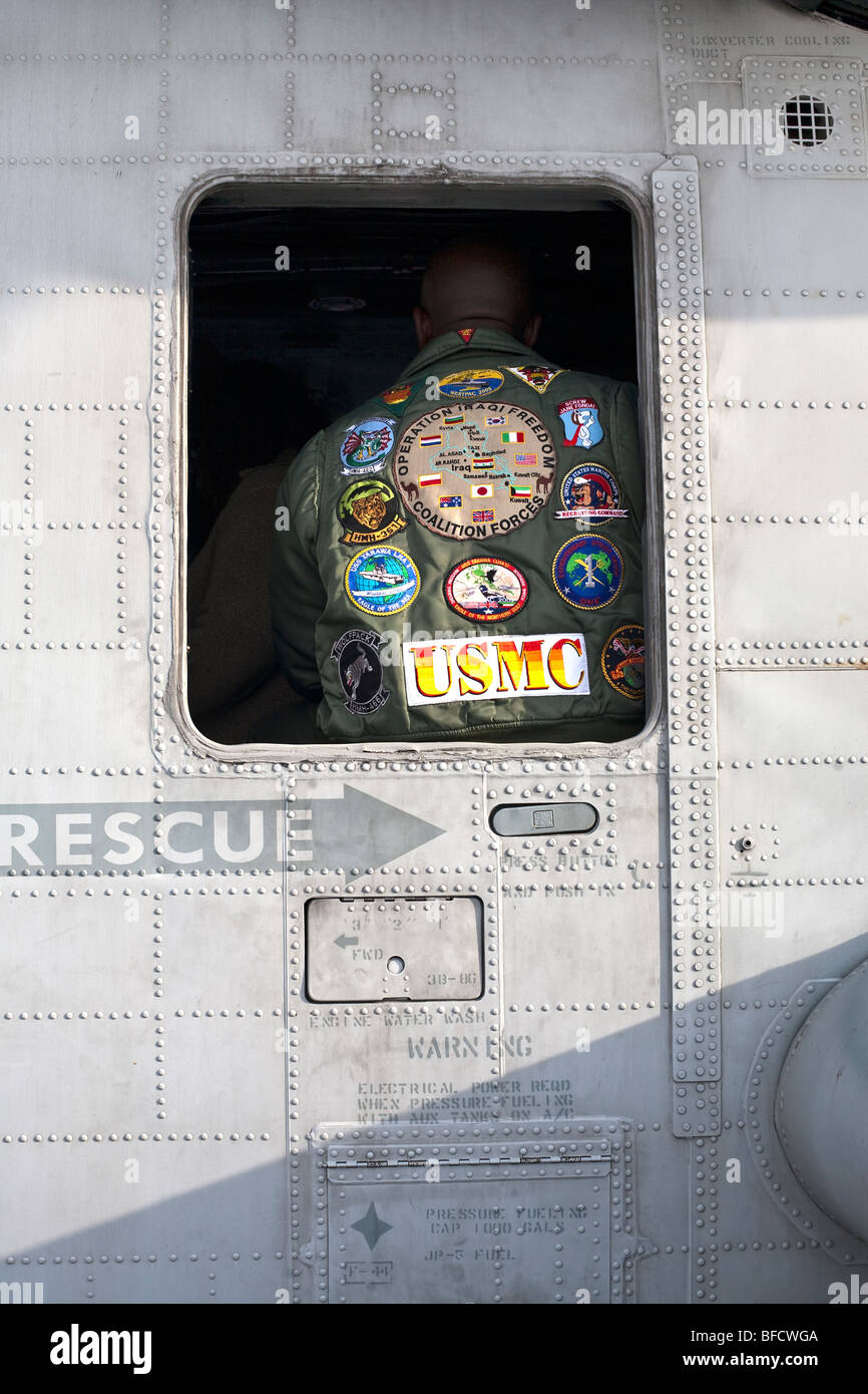 Chiudere la vista USMC insignia cucita sul retro dei Marines camicia incorniciata da una finestra di elicottero gunship sul ponte della USS New York Foto Stock