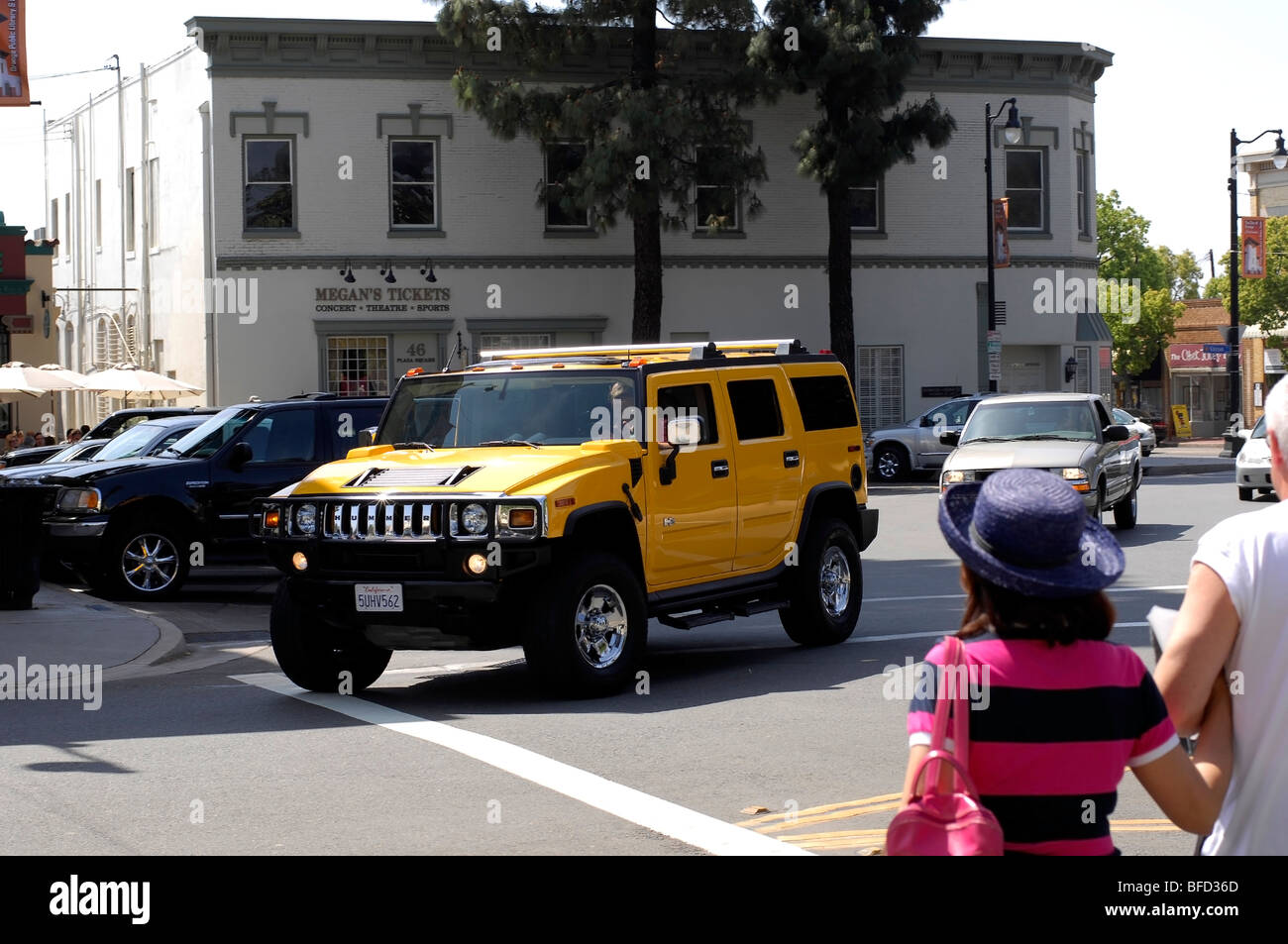 Driver aggressivi in un gas beone gira l'angolo in un giallo brillante Hummer H2. Foto Stock