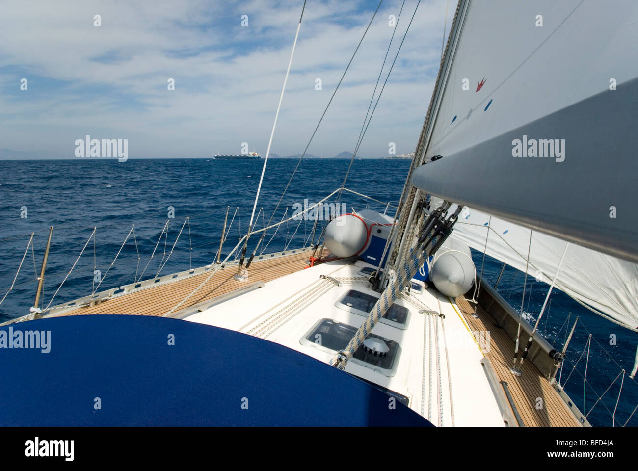 Yacht sulla porta tack, sbandata oltre, fino a vela Bodrum / Canale di Kos. Una petroliera si avvicina all'orizzonte. Giornata soleggiata con cielo blu Foto Stock