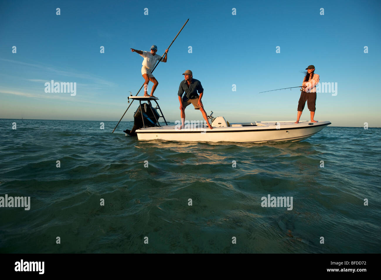 Una donna pesci mentre un uomo orologi e un uomo piloti la barca in Florida. Foto Stock