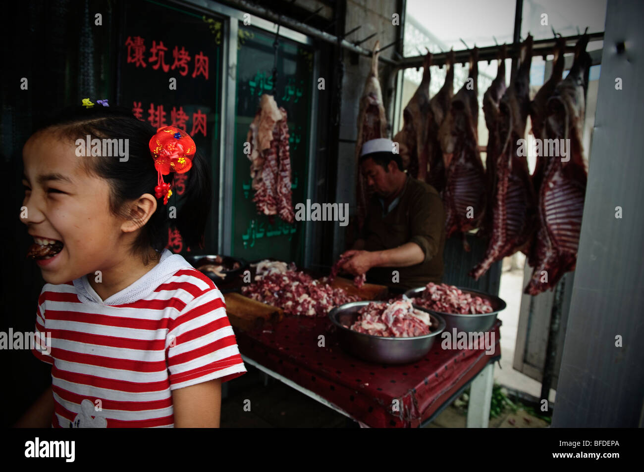 Una ragazza all'entrata di un ristorante a Kashgar, Xinjiang, Cina. Foto Stock
