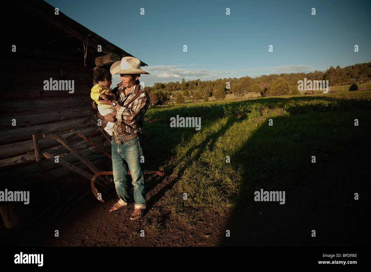 Un Tarahumara uomo tiene il suo bambino fuori della loro casa in Guachochi, Chihuahua, Messico. Foto Stock