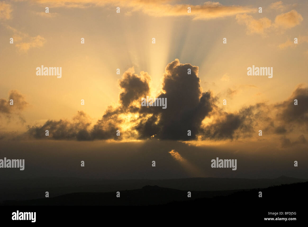Raggi di sole da dietro le nuvole scure vicino al tramonto Foto Stock