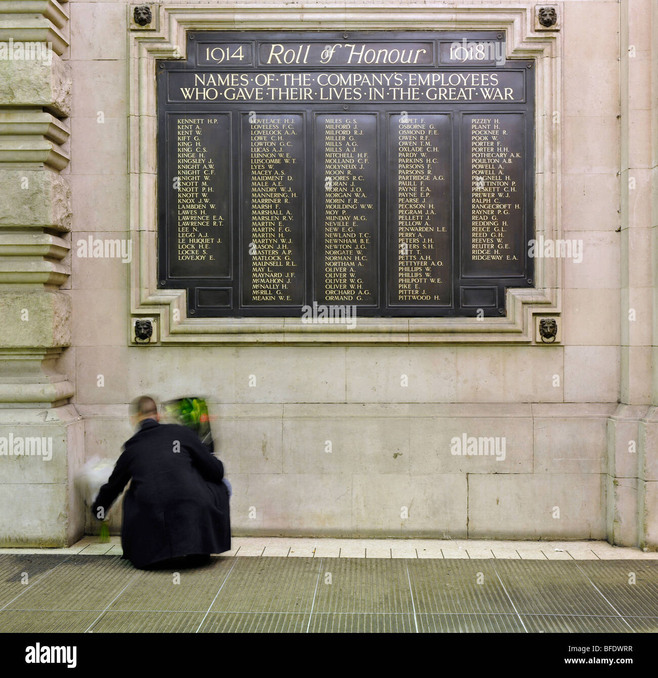 1914 - 1918 Rotolo di onore memorial presso l'entrata alla stazione di Waterloo, London, England, Regno Unito; un uomo mette fiori in memoria. Foto Stock