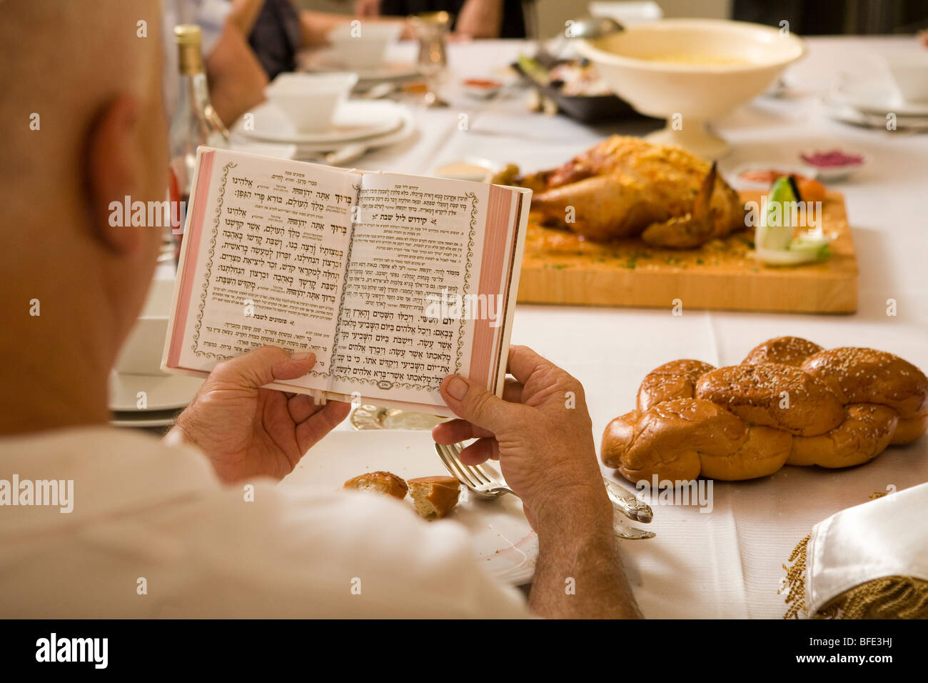 Uomo in possesso di un libro di preghiera a una cena di gala nella tabella. Foto Stock