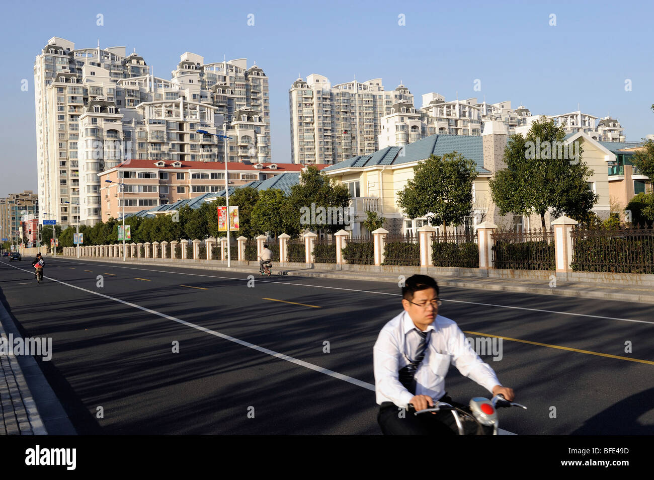 Un uomo in sella ad una bicicletta passato un composto di appartamenti di lusso e ville in Songjiang nella periferia di Shanghai. 2009 Foto Stock