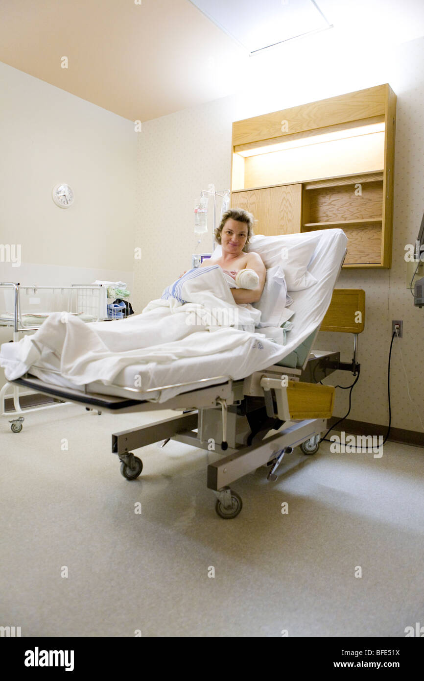 36 enne donna giaceva nel letto di ospedale con neonato nelle sue braccia, Chateauguay, Quebec, Canada Foto Stock