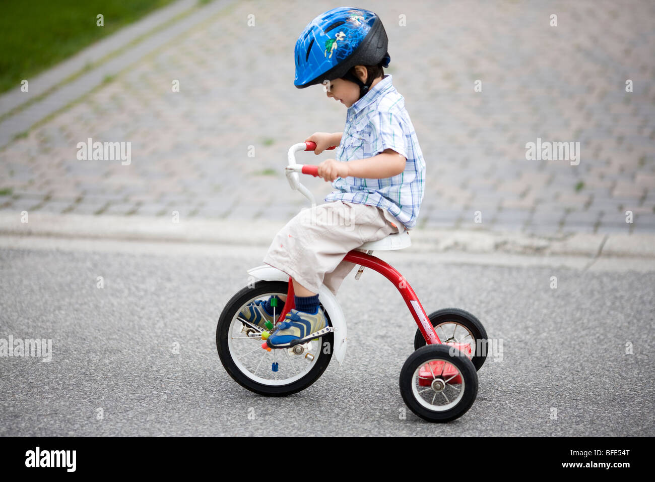 2 1/2 anno vecchio ragazzo su un triciclo e indossa un casco, Montreal, Quebec, Canada Foto Stock