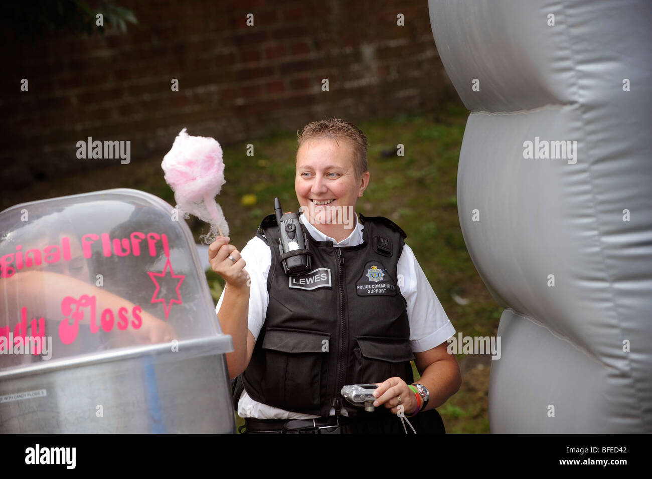 Una comunità di polizia support officer di ridere e azienda Candy Floss unisce il divertimento a una comunità evento estivo. Foto Stock