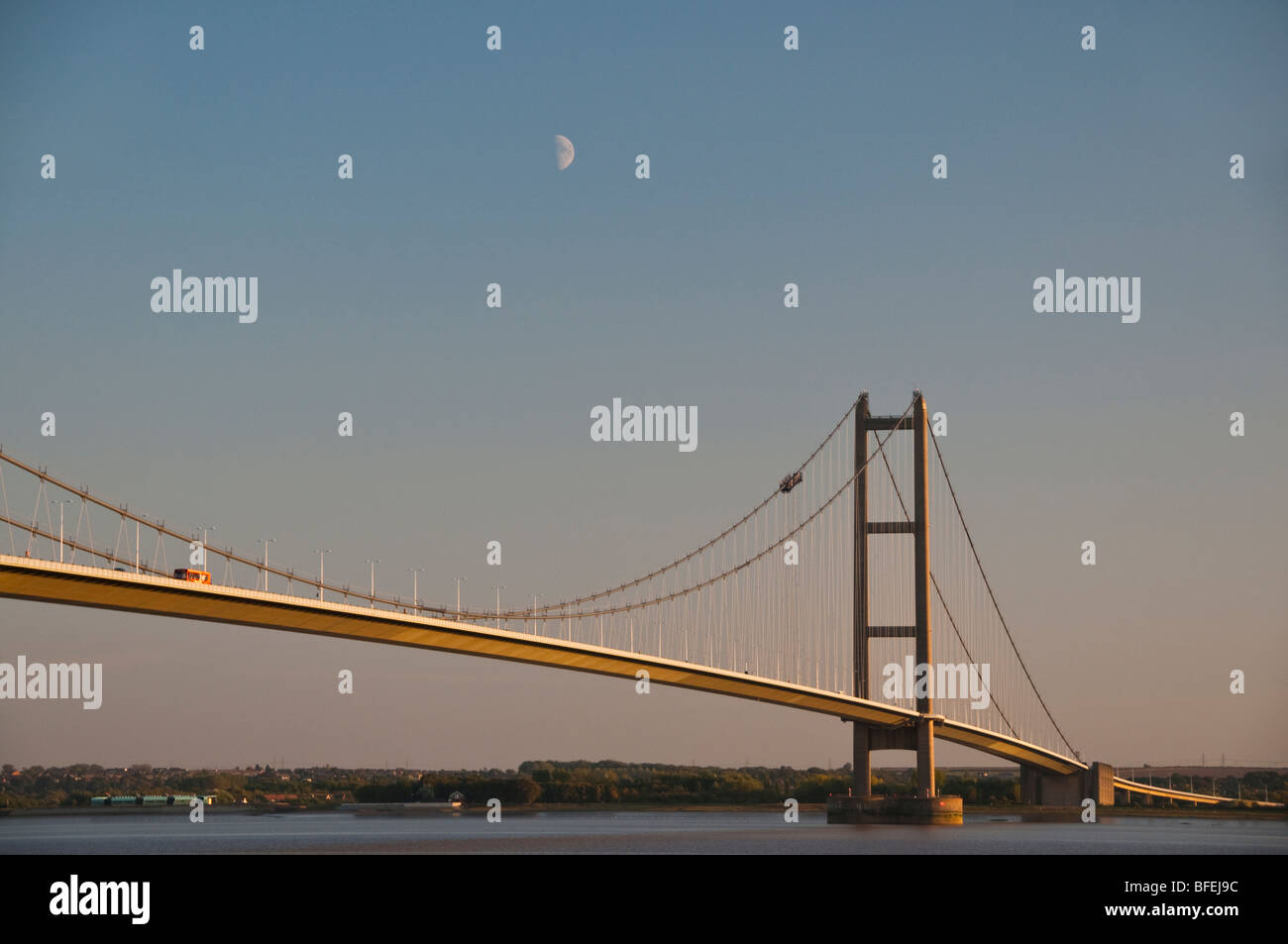 Humber Bridge con una mezza luna che mostra al di sopra di una delle torri di sostegno. Foto Stock