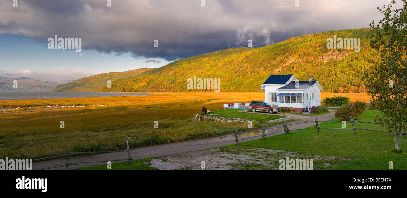 Piccola casa accanto ad una palude salata ai piedi di una grande catena montuosa in Saint-Joseph-de-la-Rive, Charlevoix, Quebec, Canada Foto Stock