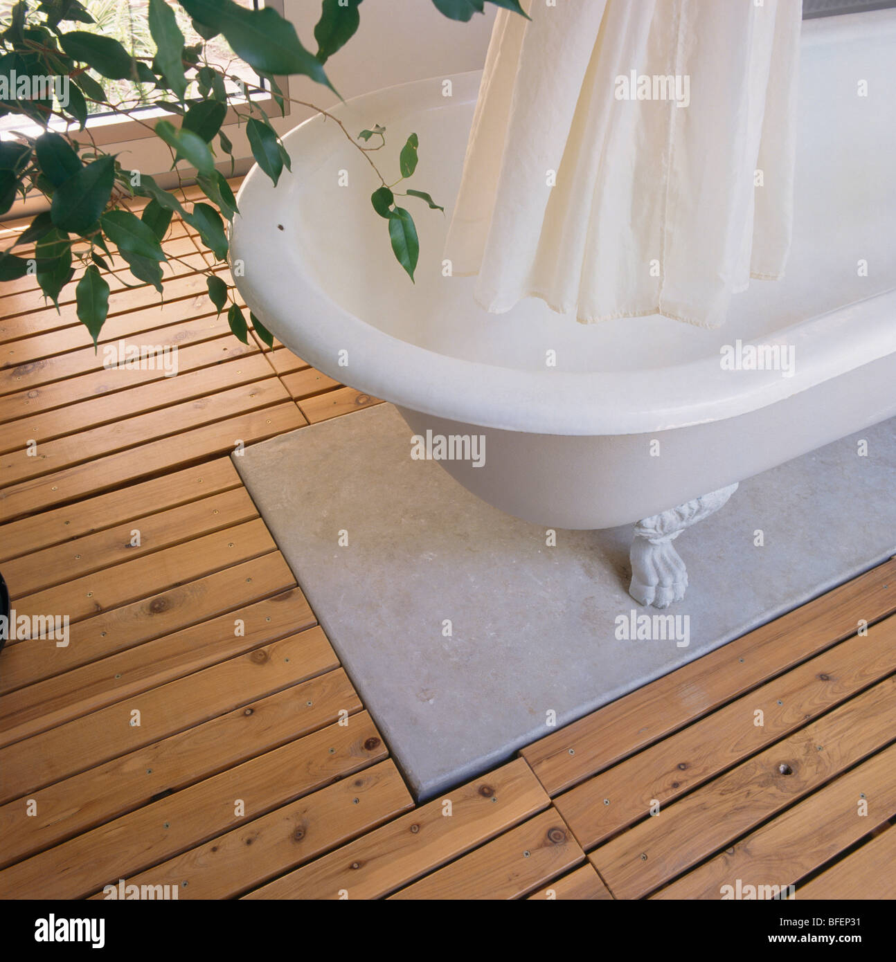 Close-up di tenda da doccia bianca e roll-top bagno in marmo e pavimenti in legno Foto Stock