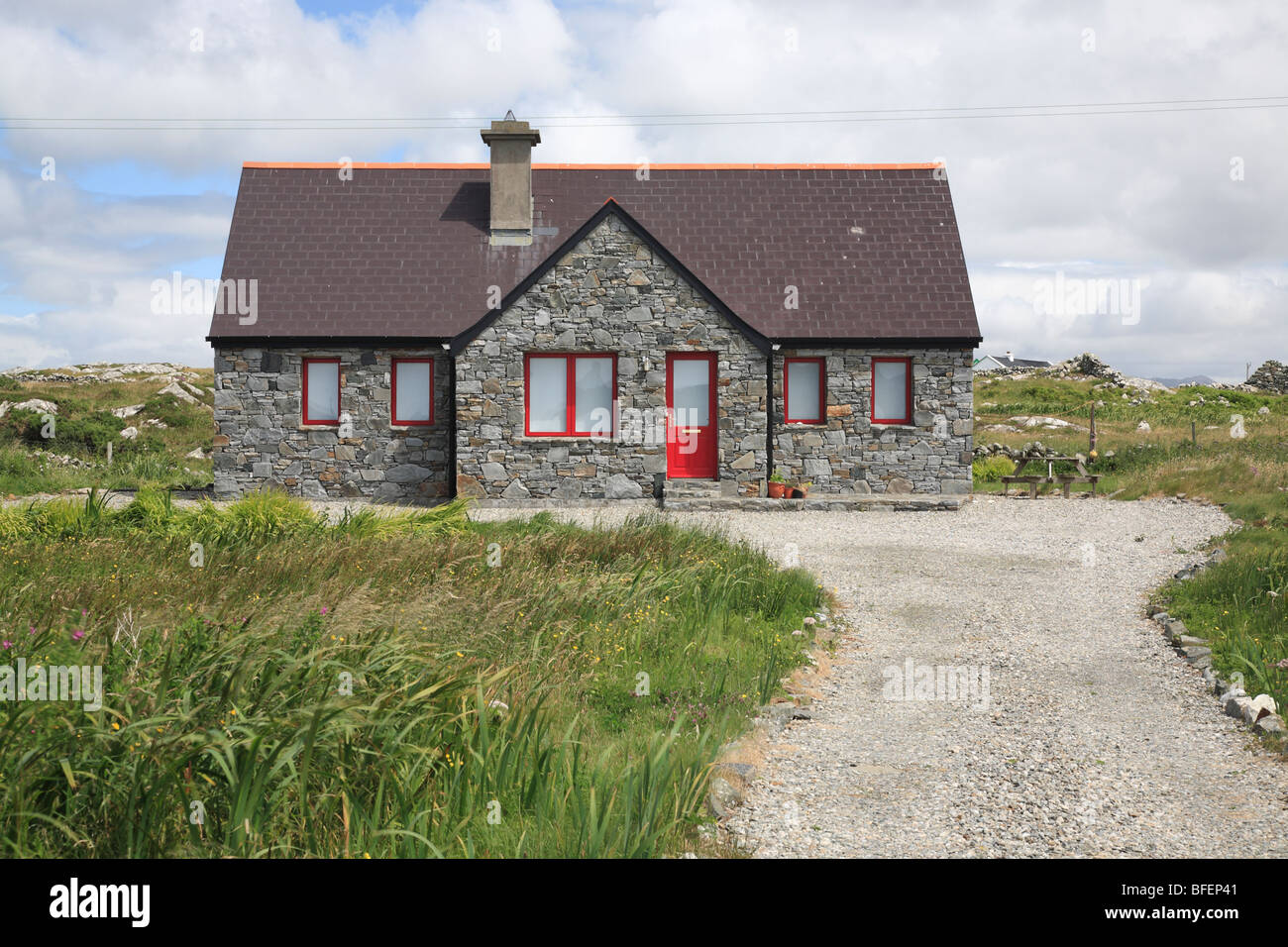 Cottage tradizionale con porta rossa in Ballyconneely costruito di pietre naturali, Connemara, Irlanda Foto Stock
