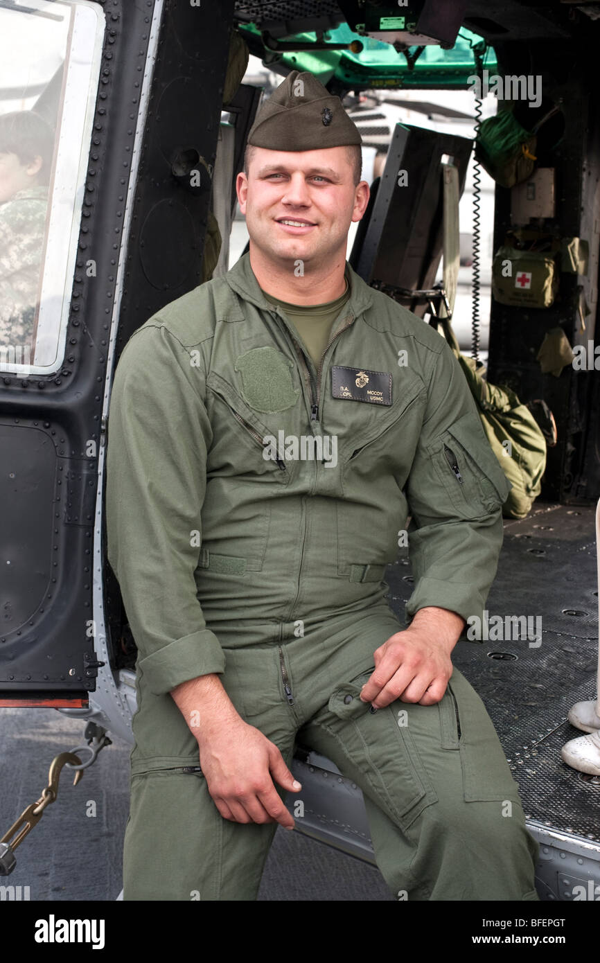 Cocky giovane caporale marine si siede alla porta di un elicottero Huey visualizzati sul ponte di volo della USS New York Foto Stock