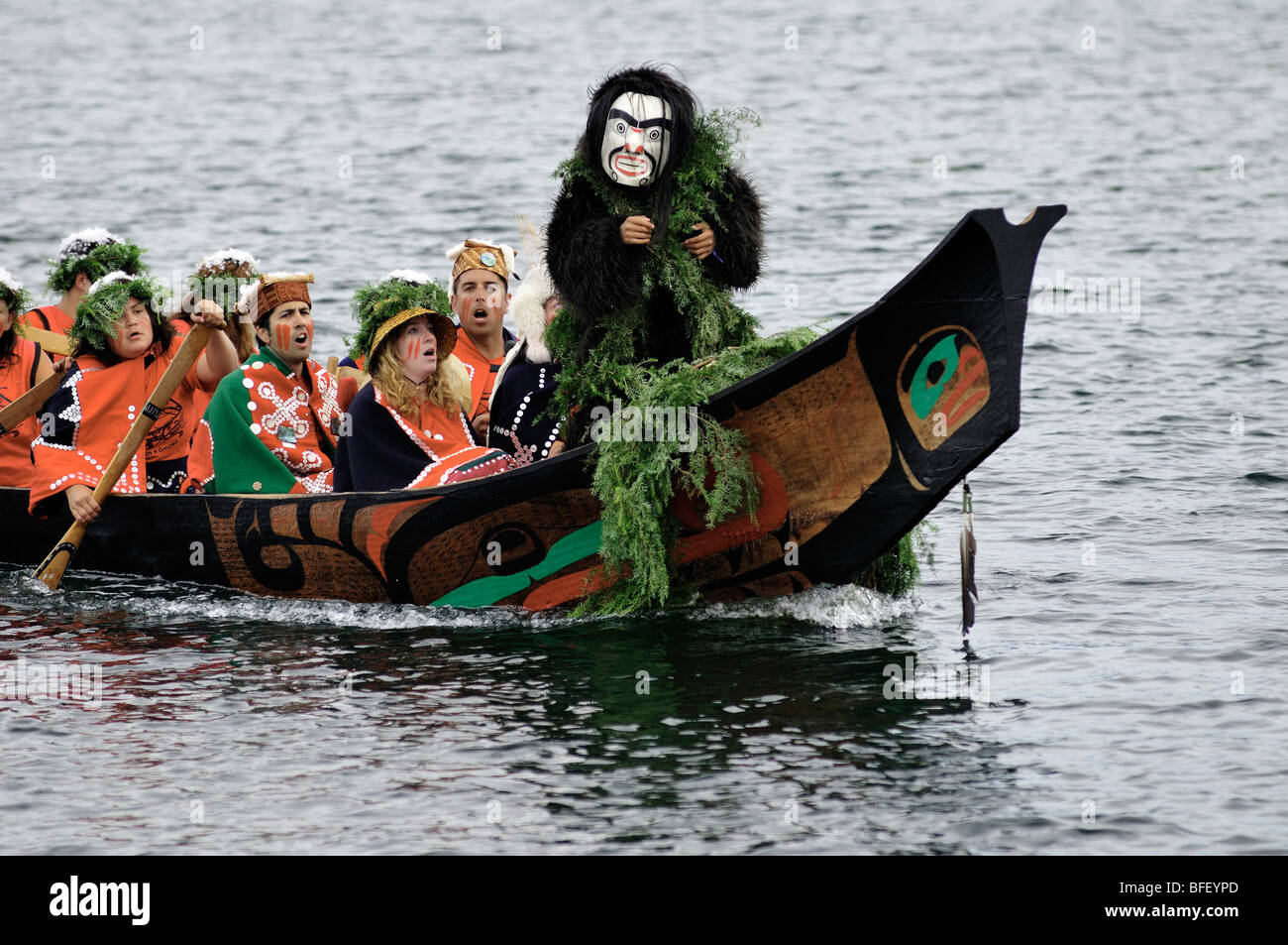 Nativo di uomo in piedi a prua di canoa con maschera bianca durante i viaggi tribali evento in Nord America giochi indigeni in Duncan. Foto Stock