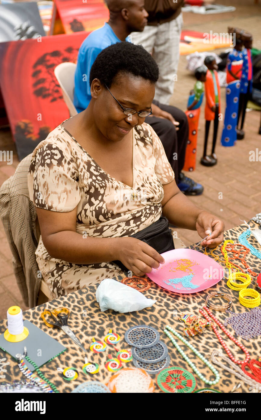 Donna che fa il tallone lacci collo. Essenwood Park Street Market. Durban, Sud Africa Foto Stock