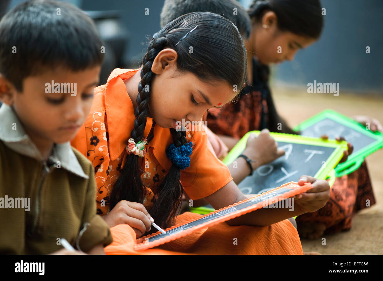 Indian School bambini seduti al di fuori della loro scuola scrivere sulle lavagne. Andhra Pradesh, India Foto Stock