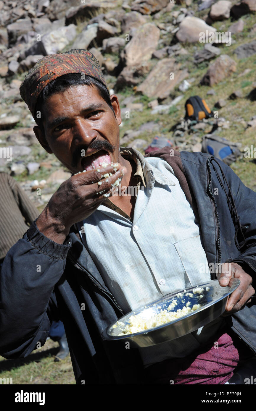 Un portiere nepalese di mangiare la prima colazione prima di una lunga giornata sulle colline che trasportano 50kg per escursionisti. Foto Stock