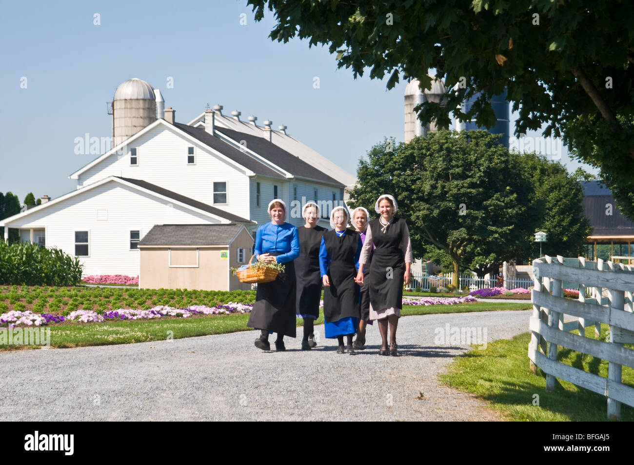 Giovani donne amish amici percorrendo a piedi il paese lane road in Lancaster PA. casalinghe Foto Stock