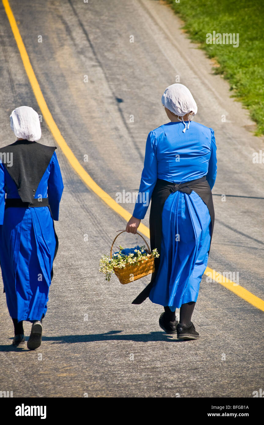 Giovani donne amish amici percorrendo a piedi il paese lane road in Lancaster PA. casalinghe Foto Stock