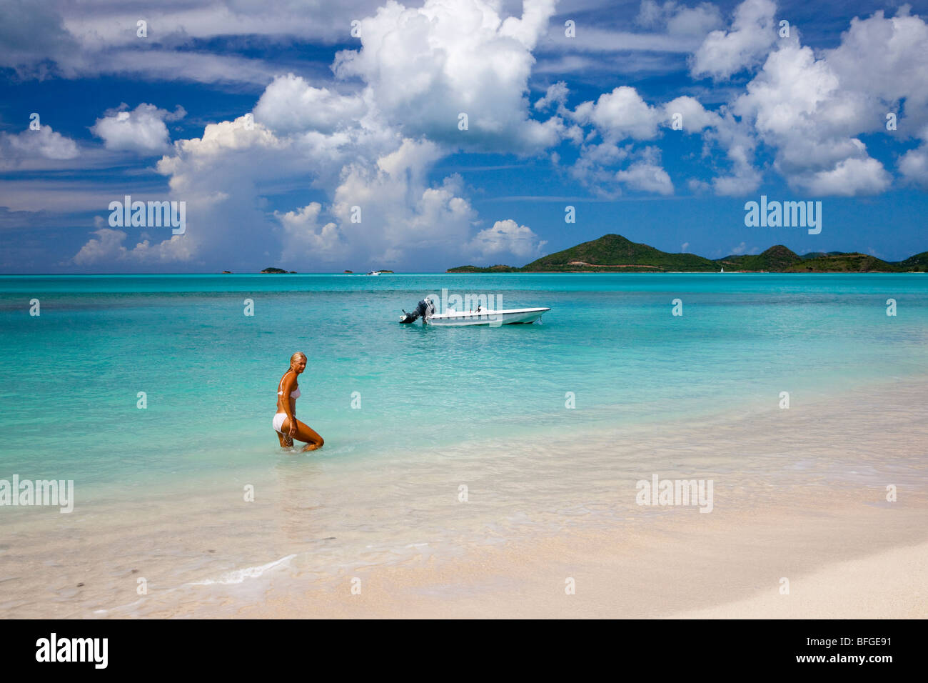 Ffryes Bay con Pearns punto all'orizzonte, Antigua con barca a motore e la giovane donna in bikini in mare Foto Stock