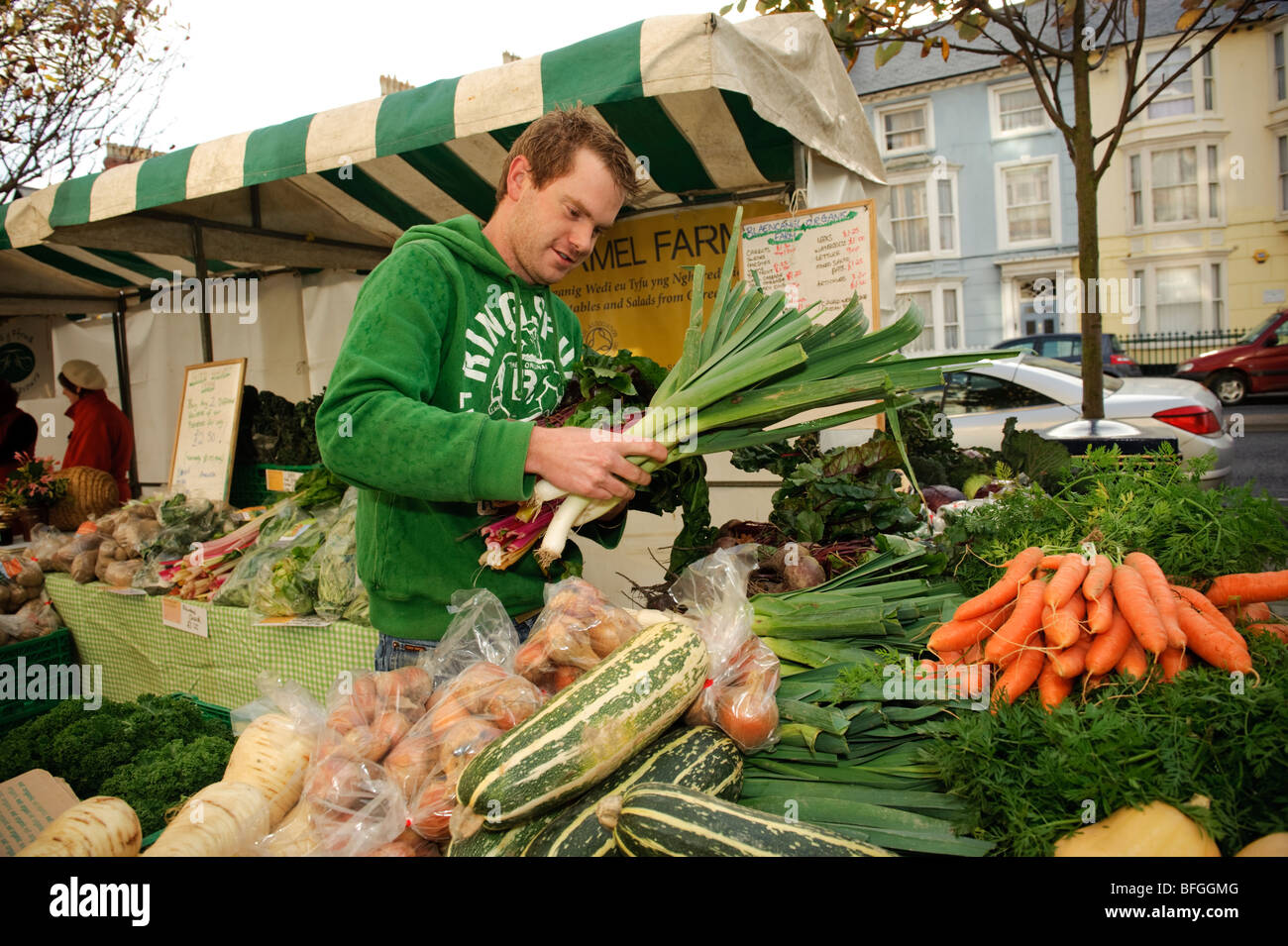 Giovane uomo l'acquisto o la vendita di prodotti locali freschi ortaggi a Aberystwyth farmers market, Ceredigion, Wales UK Foto Stock