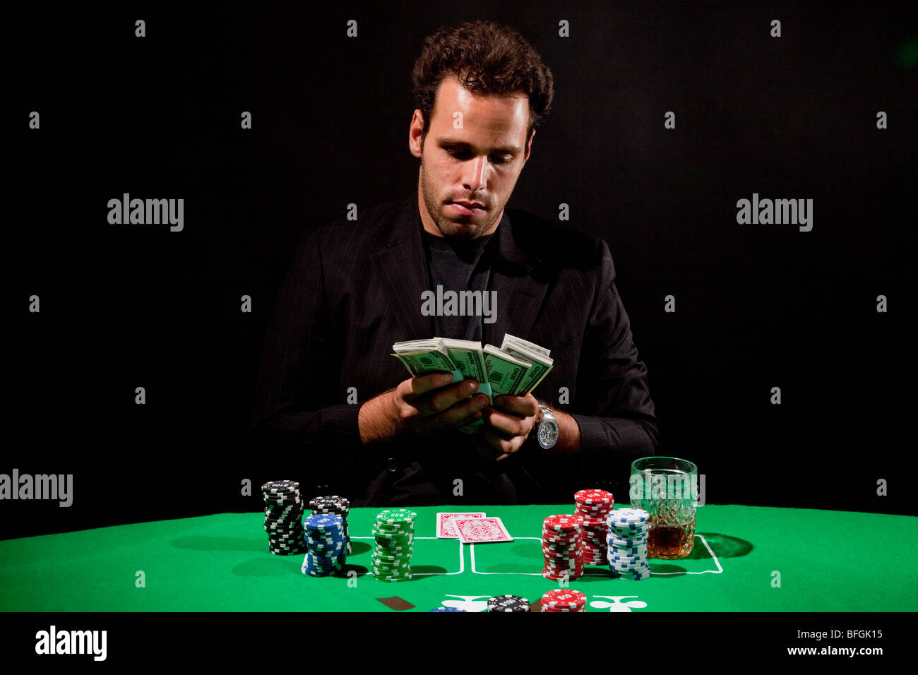 Un giovane maschio giocatore al tavolo da gioco conta il suo denaro modello di rilascio disponibili Foto Stock