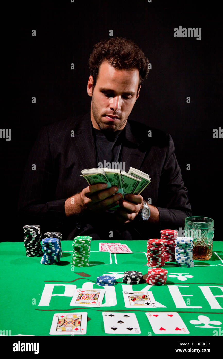Un giovane maschio giocatore al tavolo da gioco conta il suo denaro modello di rilascio disponibili Foto Stock