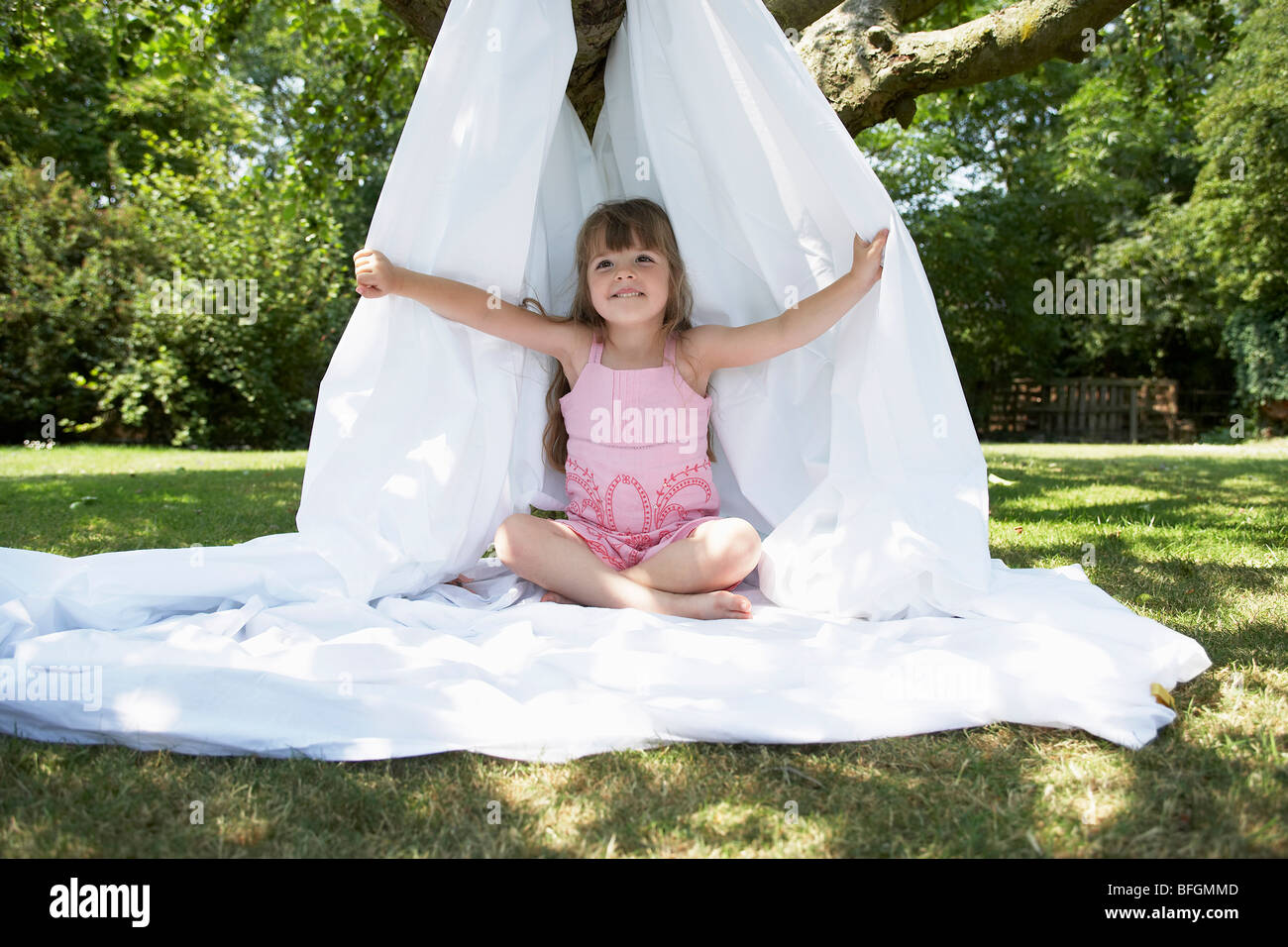 Giovane ragazza nel cortile posteriore seduto in tenda realizzata di lamiera letto Foto Stock