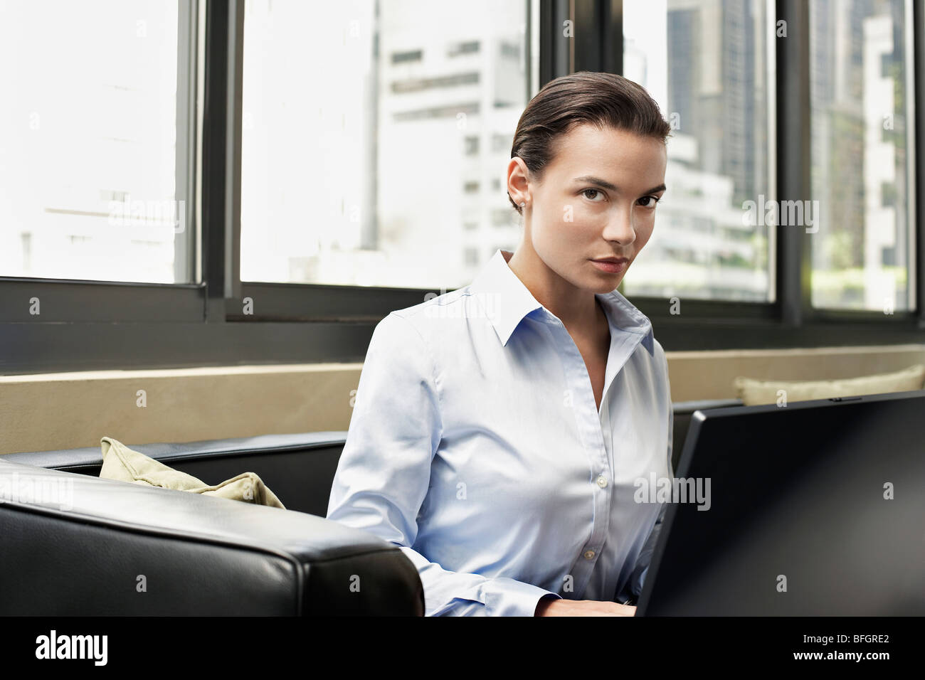 Business donna seduta su un divano con lap top Foto Stock