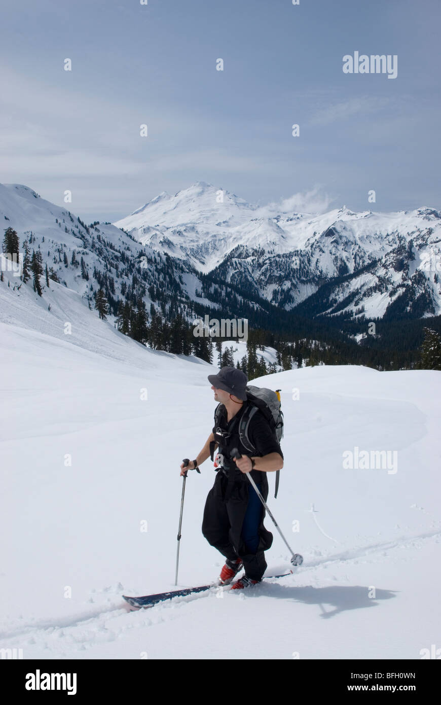 Skiier rendendo la sua strada verso il Monte Ann in una calda giornata di primavera con Mt Baker in distanza Mt Baker deserto Snoqualmie nazionali per Foto Stock