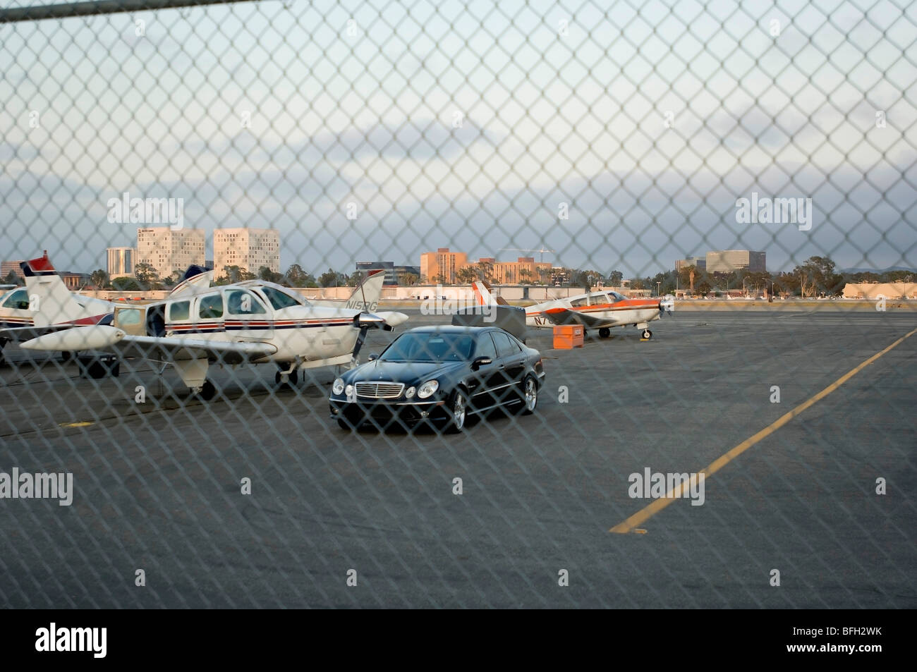 Dietro il recinto aeroportuale, un uomo può essere visto all'interno del pozzetto del suo motore unico aereo privato svolgendo attività di preflight. Foto Stock