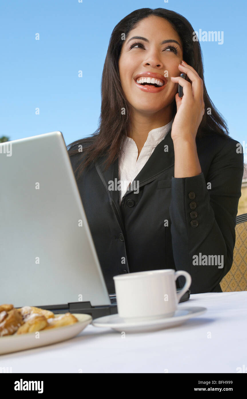 La metà degli adulti donna business parlando al telefono nella parte anteriore del computer portatile Foto Stock