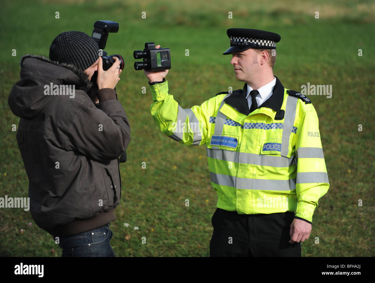 Una pressa fotografo prende le immagini di un poliziotto con una mano la telecamera spped Foto Stock