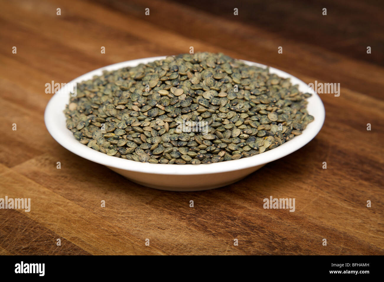 Ingredienti di cottura Lentil semi in una ciotola bianca su una superficie di lavoro della cucina. Foto Stock