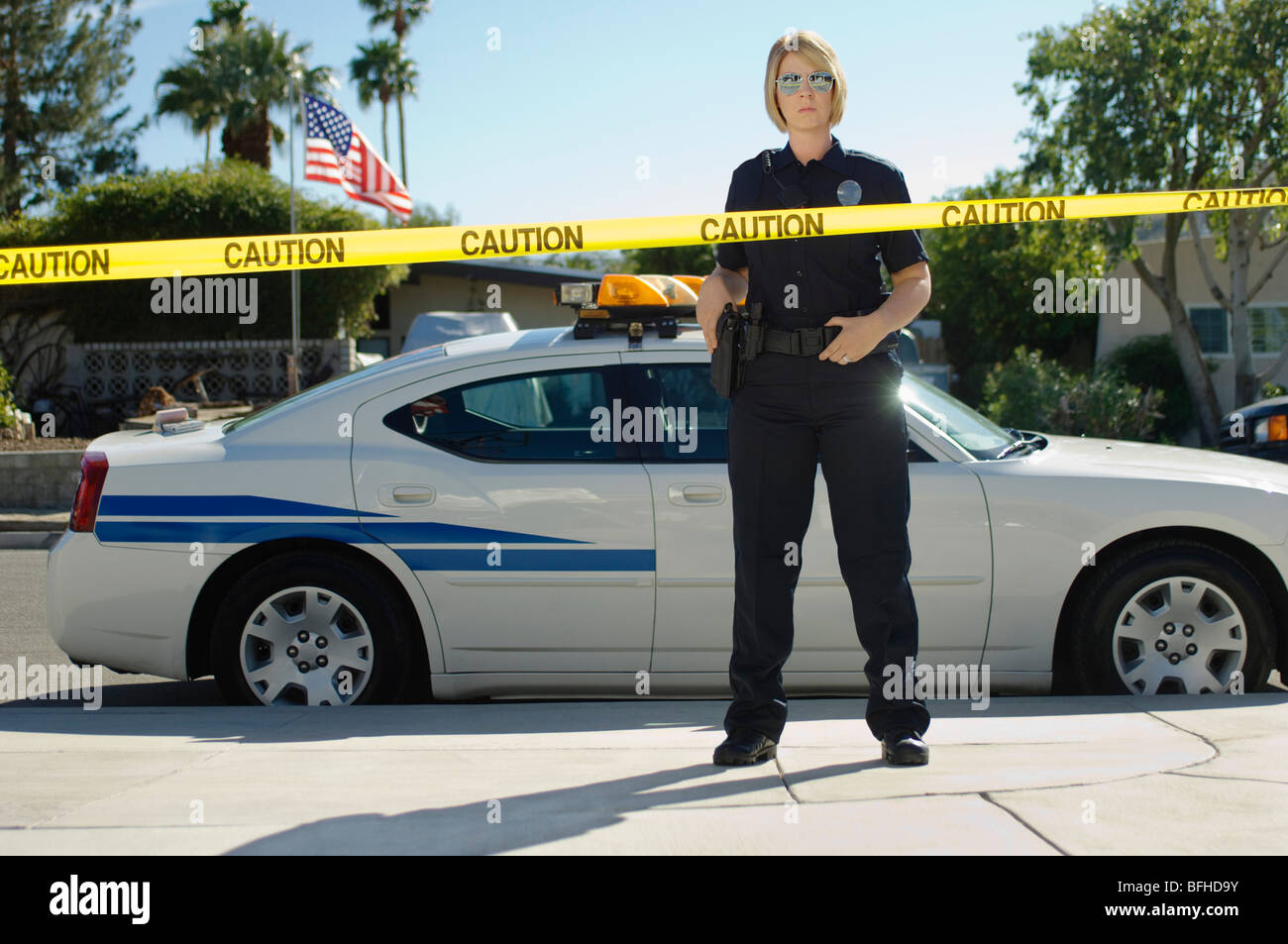 Funzionario di polizia in piedi dietro il nastro di polizia Foto Stock
