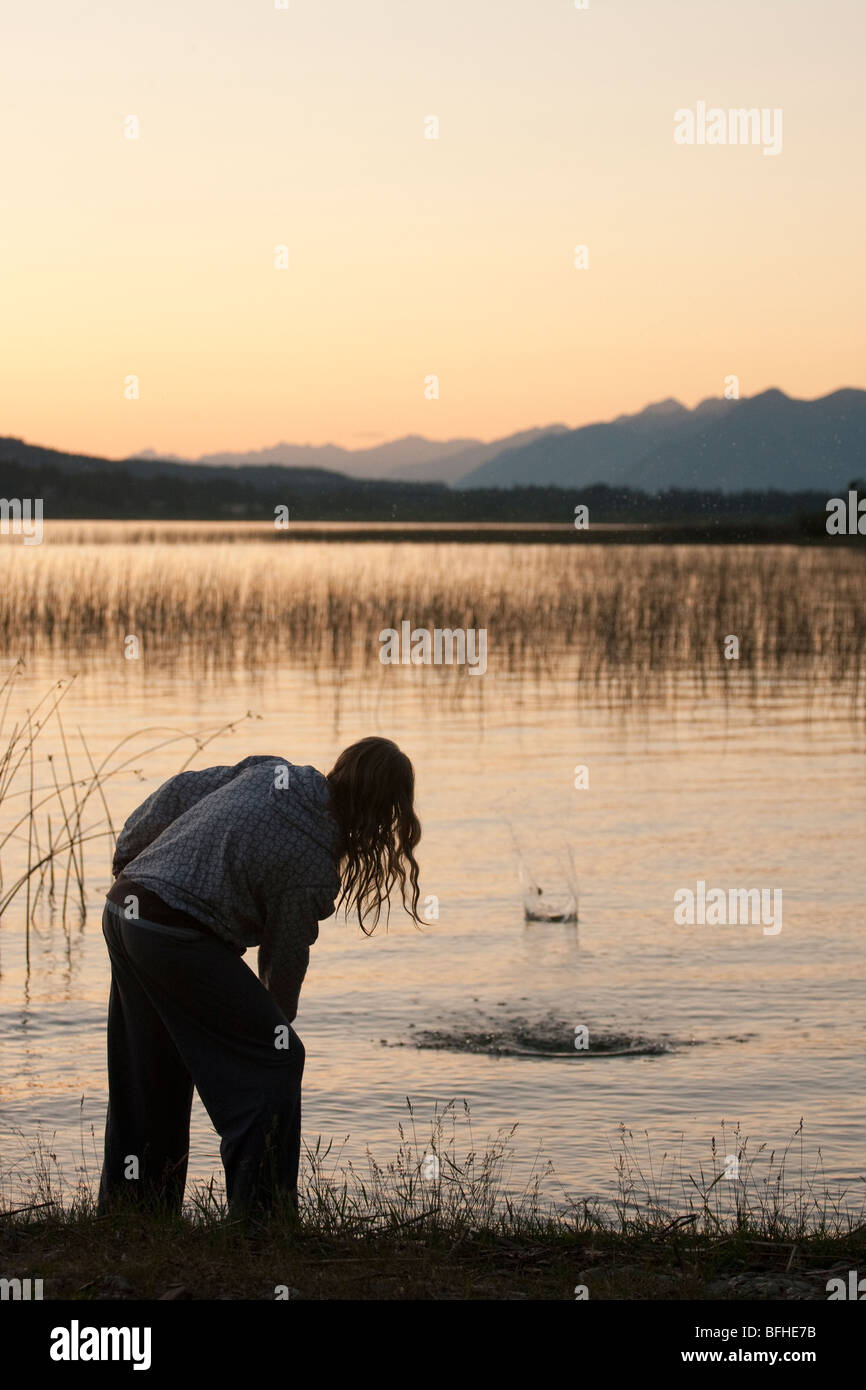 Una femmina di salta alcune rocce sul lago Columbia come il sole tramonta Foto Stock