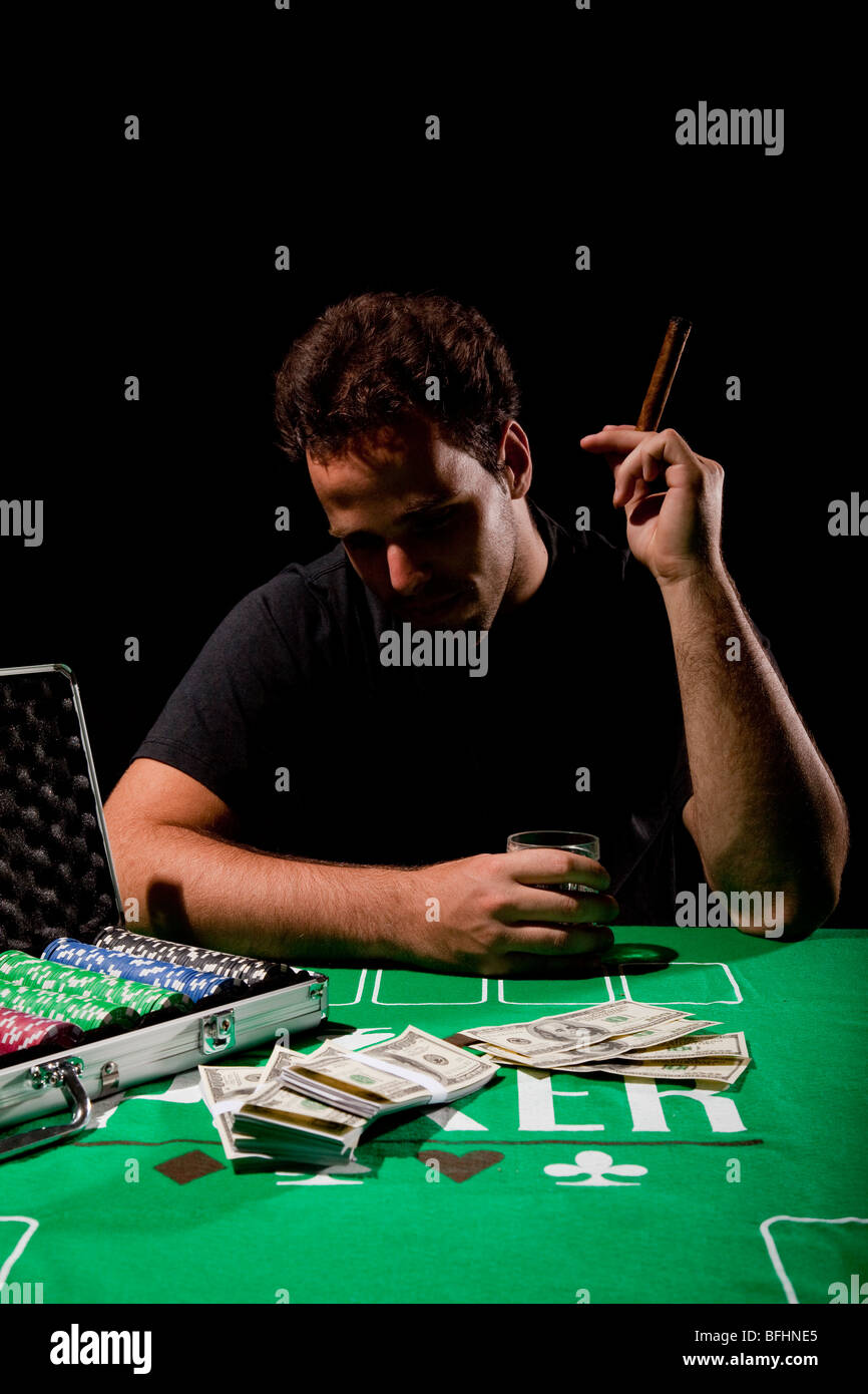 Un giovane maschio giocatore al tavolo da gioco tenendo un sigaro modello di rilascio disponibili Foto Stock