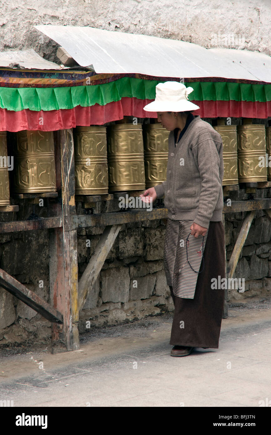 Donna tibetana pellegrino buddista eseguendo il Potala kora girando le ruote della preghiera in Lhasa Foto Stock