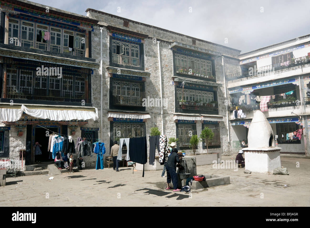 Zona della città vecchia di Lhasa il Tibet che mostra il lavaggio della pompa dell'acqua in una piazza residenziale con fumatori santuario Foto Stock