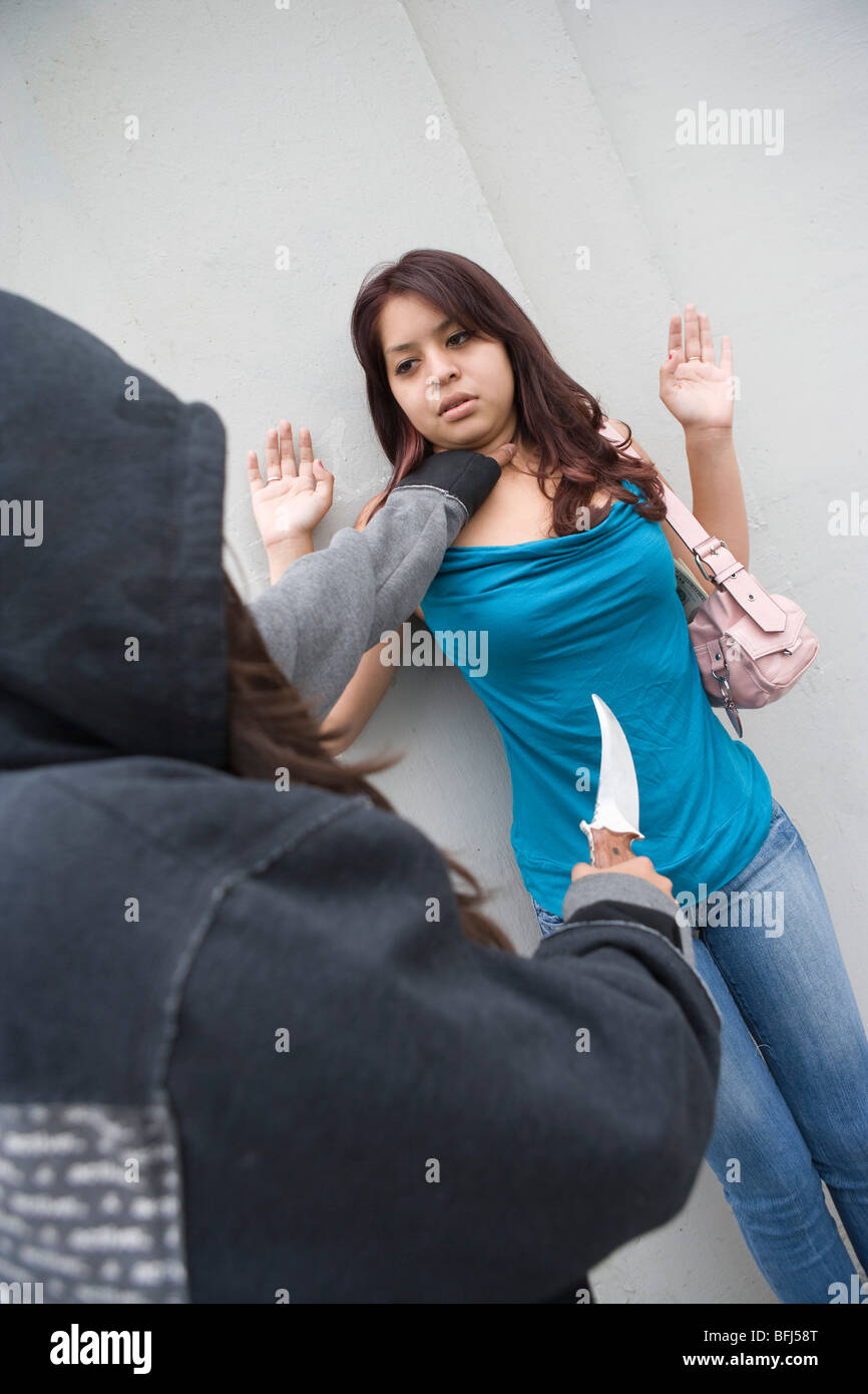 Donna con cappuccio rubando la giovane donna con il coltello Foto Stock