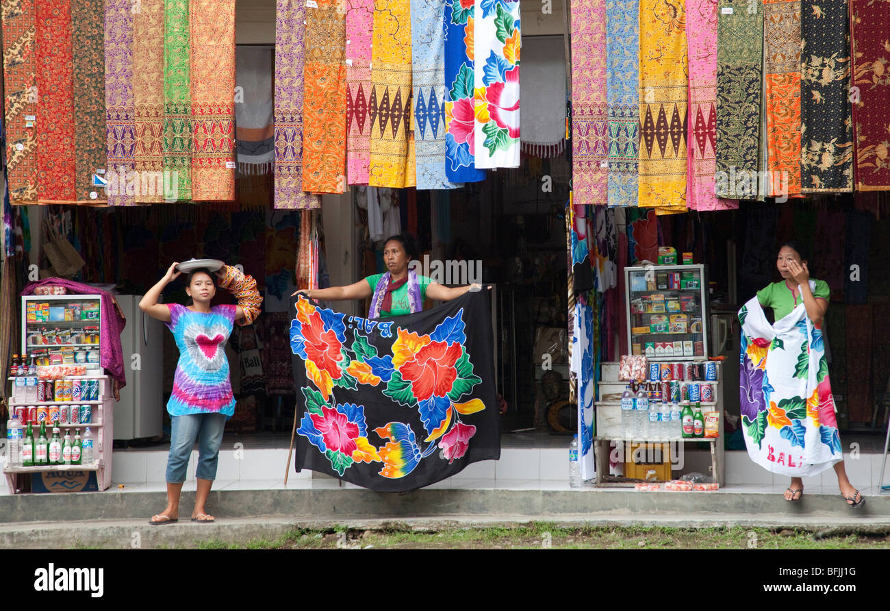 Onorevoli Balinese vendere vivacemente colorato tessile, abbigliamento, sciarpe etc, Bali, Indonesia Foto Stock
