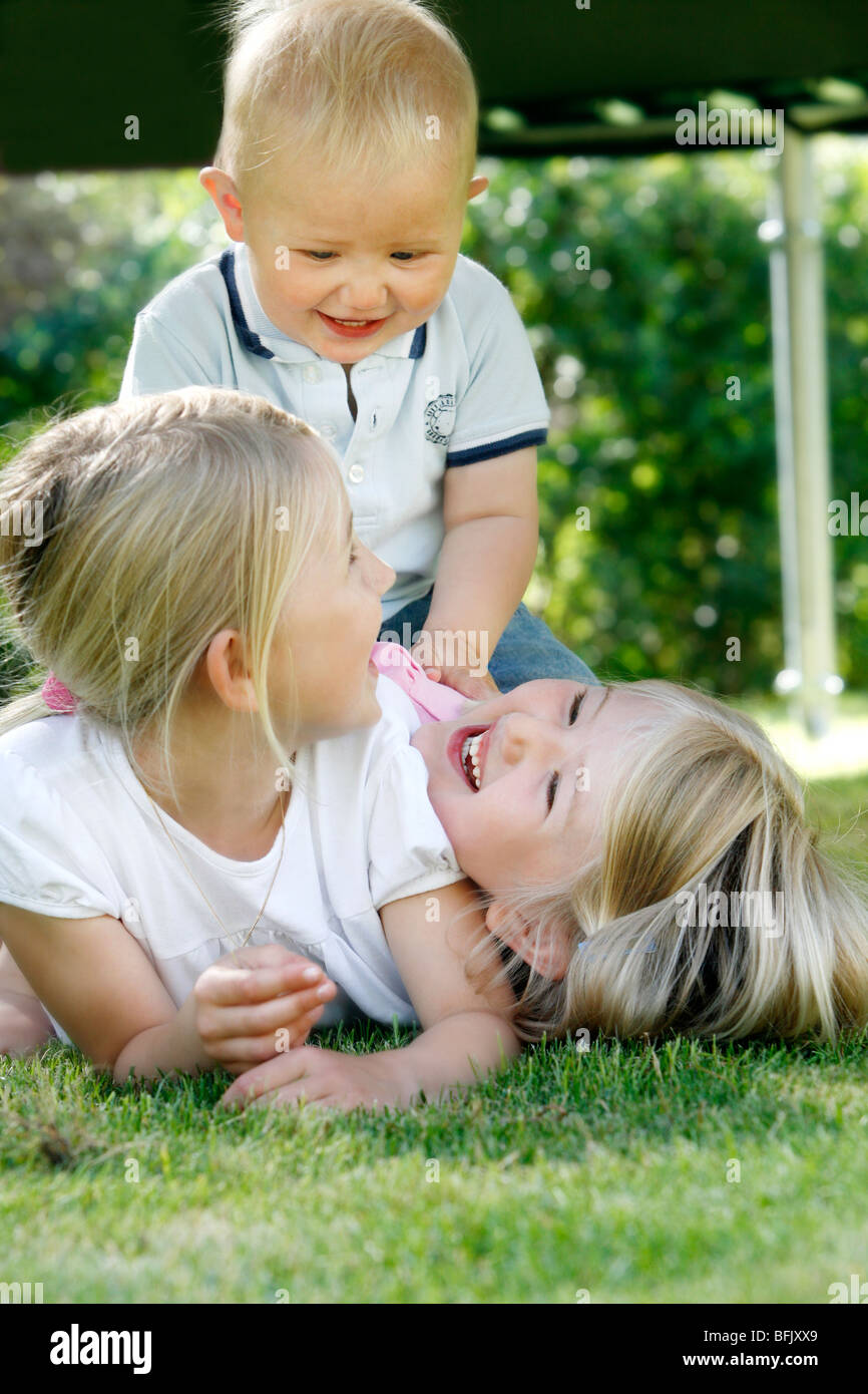 Tre fratelli bionda giochi nel giardino, Svezia. Foto Stock